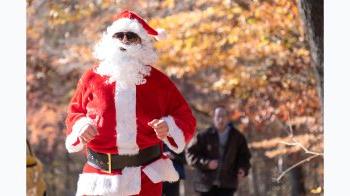 A man in a Santa costume jogging.