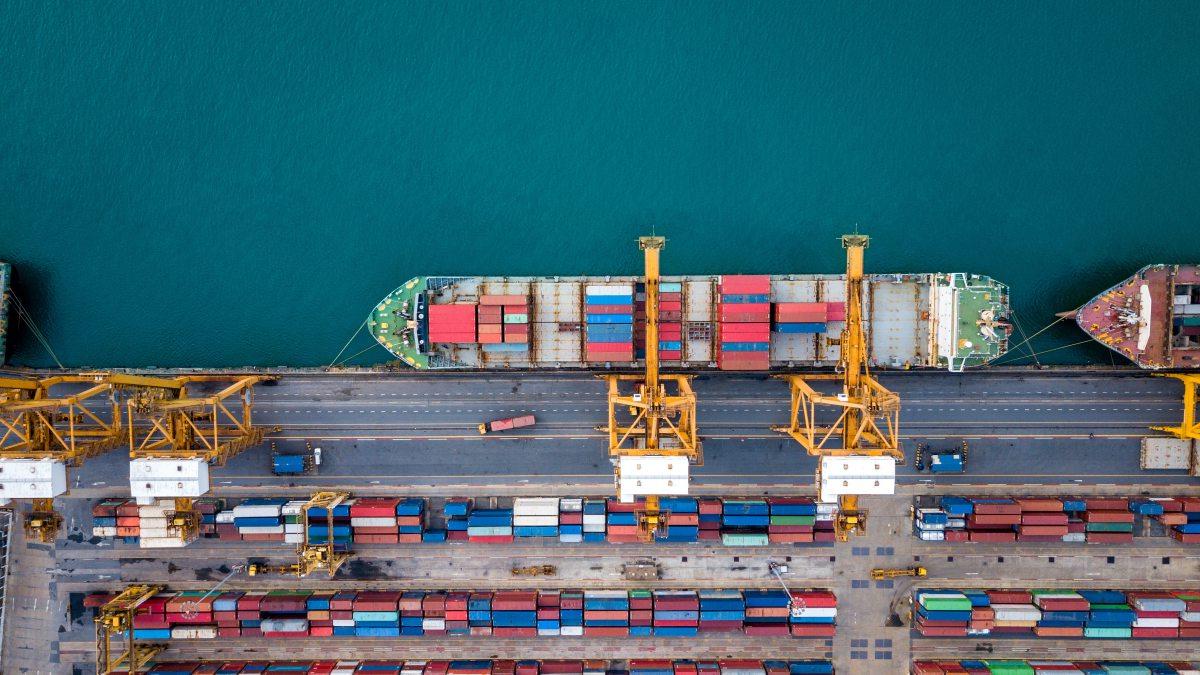 Top view of international port with Crane loading containers in import export business logistics.